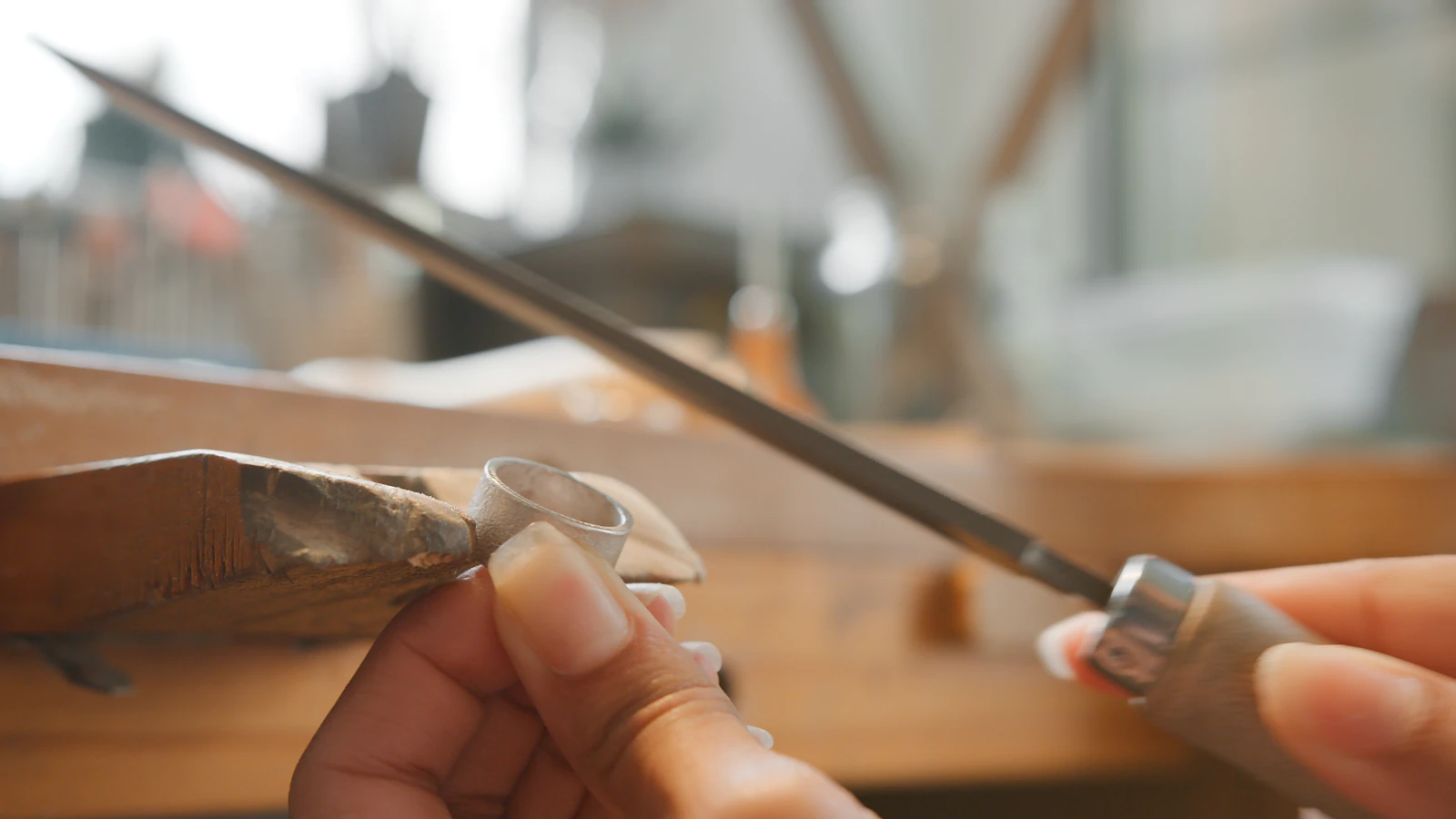 Jeweler hand-filing a silver ring at a workbench